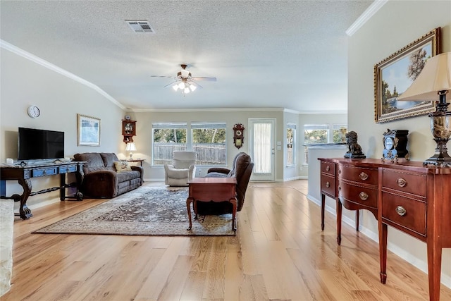 living area with wood finished floors, ornamental molding, ceiling fan, a textured ceiling, and baseboards