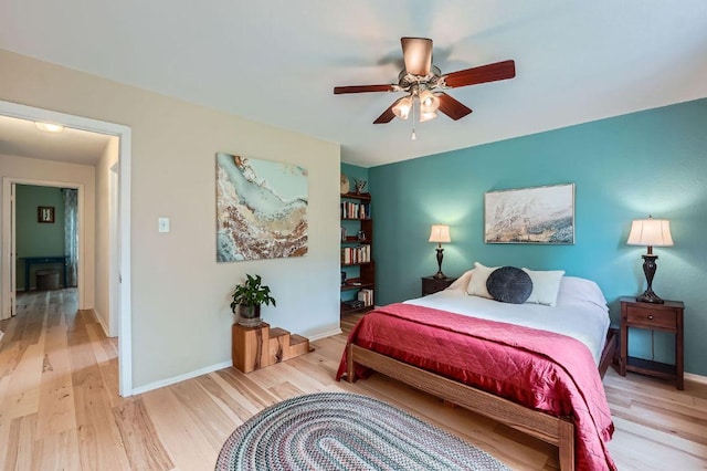 bedroom featuring light wood finished floors, baseboards, and a ceiling fan