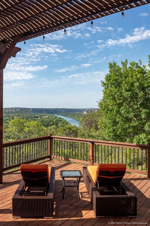 wooden deck with a water view, a forest view, and an outdoor living space