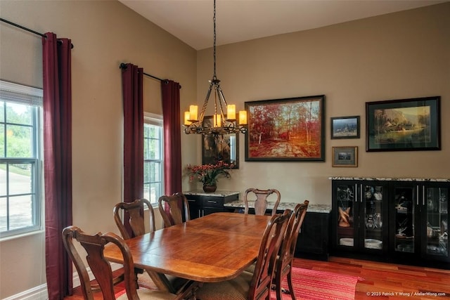 dining room with a chandelier, healthy amount of natural light, and wood finished floors