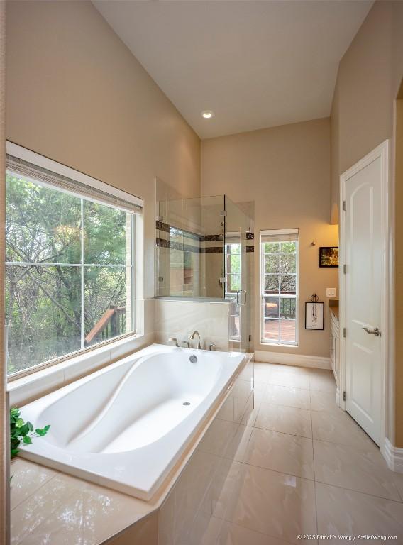 bathroom with a stall shower, a bath, baseboards, and a towering ceiling