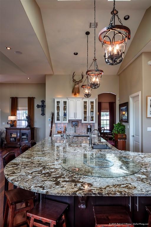 14305 Fallen Timber Dr, Austin, TX 78734 - kitchen with a sink, a chandelier, light stone counters, lofted ceiling, and white cabinets