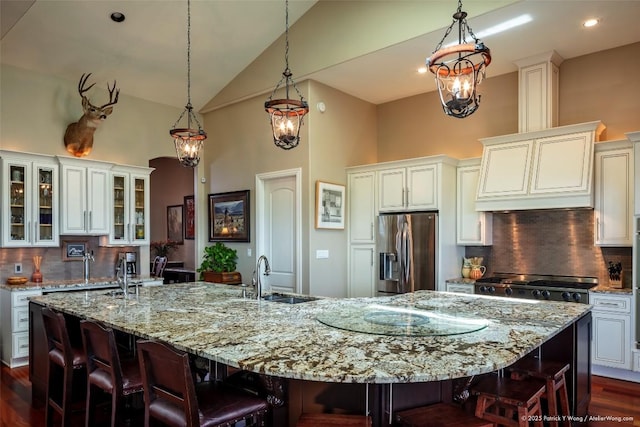 kitchen featuring stainless steel fridge, a sink, high vaulted ceiling, a breakfast bar, and decorative backsplash