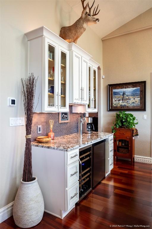14305 Fallen Timber Dr, Austin, TX 78734 - bar area with beverage cooler, dark wood-style floors, decorative backsplash, vaulted ceiling, and baseboards