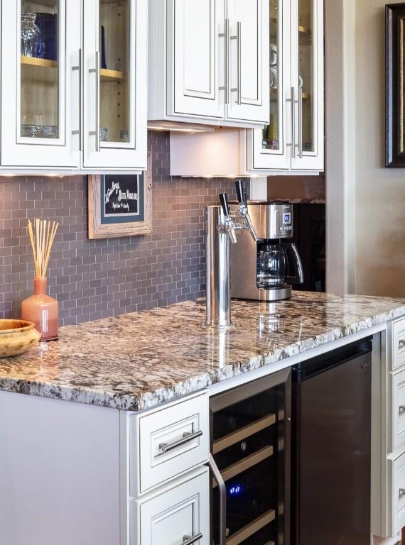 14305 Fallen Timber Dr, Austin, TX 78734 - kitchen featuring wine cooler, white cabinetry, light stone counters, and decorative backsplash
