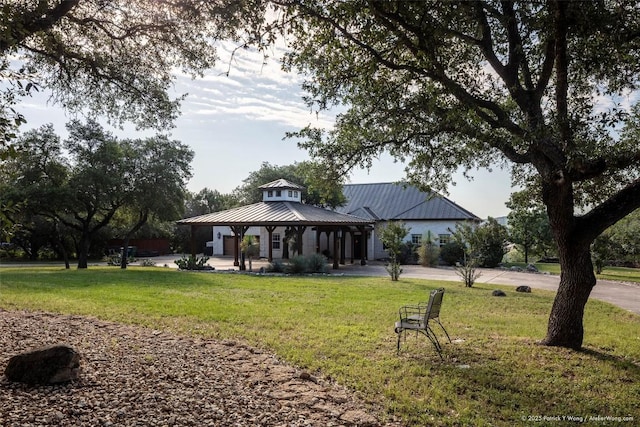 rear view of property with a gazebo, a yard, and metal roof