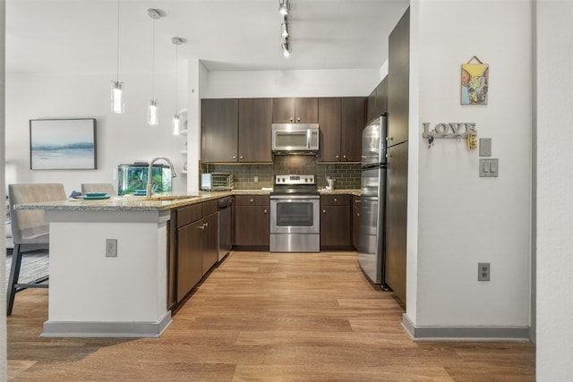 1900 Barton Springs Rd Unit 2023, Austin, TX 78704 - kitchen with stainless steel appliances, a peninsula, light wood-style flooring, tasteful backsplash, and dark brown cabinets