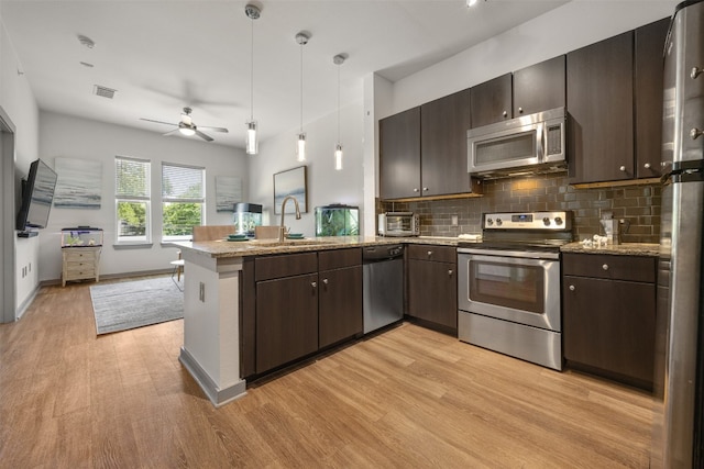 1900 Barton Springs Rd Unit 2023, Austin, TX 78704 - kitchen featuring appliances with stainless steel finishes, a peninsula, light wood finished floors, ceiling fan, and open floor plan