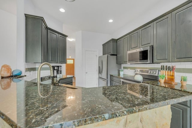 265 Makaha Dr, Bastrop, TX 78602 - kitchen with appliances with stainless steel finishes, backsplash, a sink, dark stone countertops, and recessed lighting