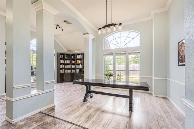 home office featuring ornamental molding, baseboards, wood finished floors, arched walkways, and a textured wall