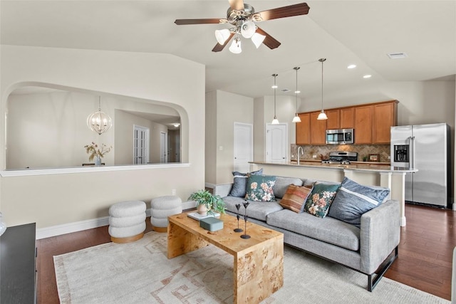 living room featuring arched walkways, wood finished floors, lofted ceiling, ceiling fan, and baseboards