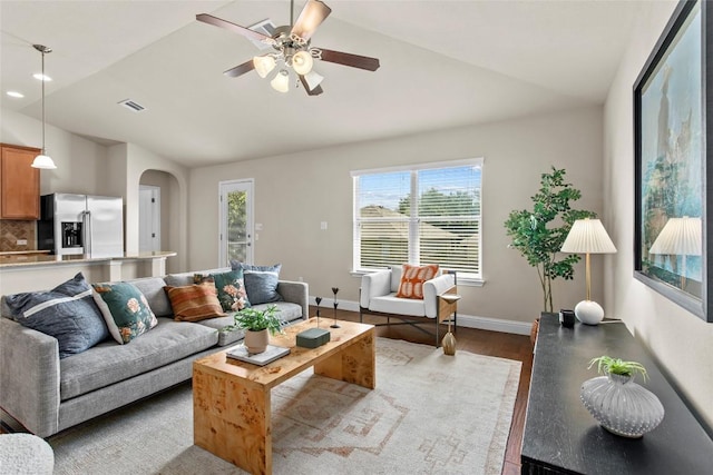 living area featuring vaulted ceiling, plenty of natural light, arched walkways, ceiling fan, and wood finished floors