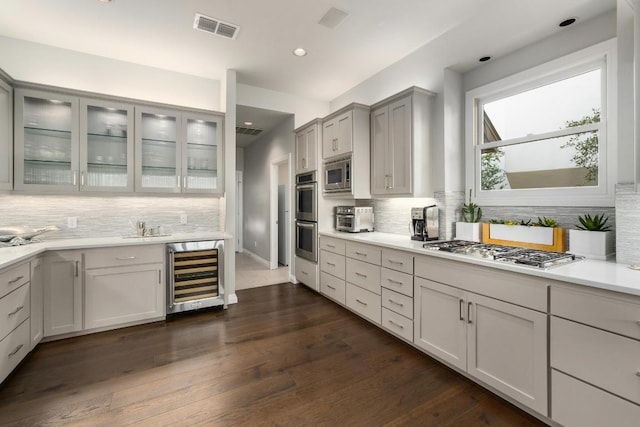 6605 W Courtyard Dr, Austin, TX 78730 - kitchen featuring wine cooler, appliances with stainless steel finishes, decorative backsplash, light countertops, and glass insert cabinets
