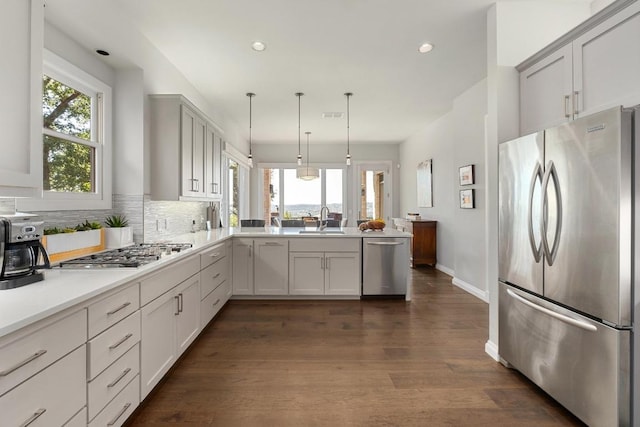 6605 W Courtyard Dr, Austin, TX 78730 - kitchen with stainless steel appliances, a sink, a peninsula, decorative backsplash, and dark wood-style flooring