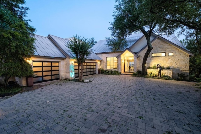 6605 W Courtyard Dr, Austin, TX 78730 - view of front facade with a standing seam roof, stone siding, a garage, decorative driveway, and a metal roof