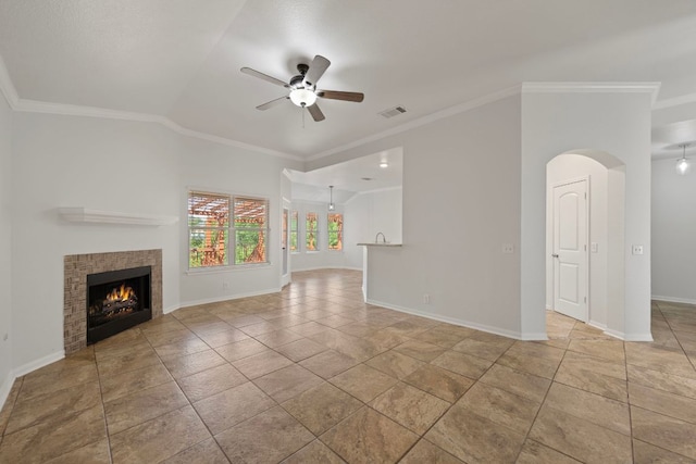 118 Cassandra Dr, Hutto, TX 78634 - unfurnished living room featuring a ceiling fan, baseboards, crown molding, a tiled fireplace, and arched walkways
