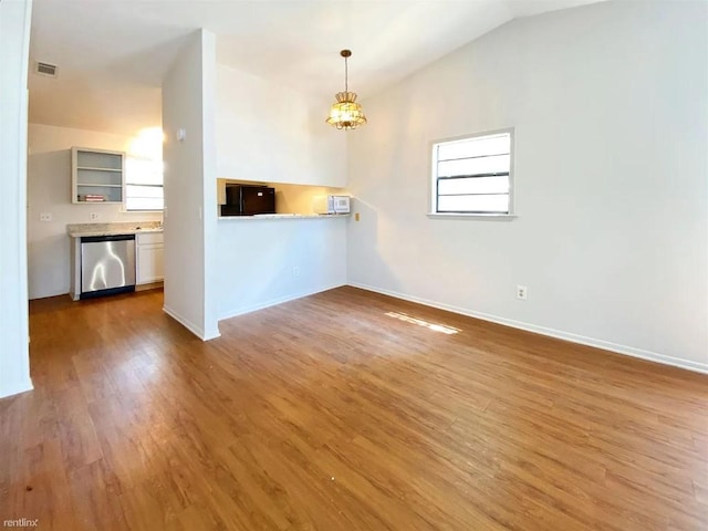 1604 Mill St Unit B, San Marcos, TX 78666 - unfurnished living room featuring a chandelier, wood finished floors, baseboards, and vaulted ceiling