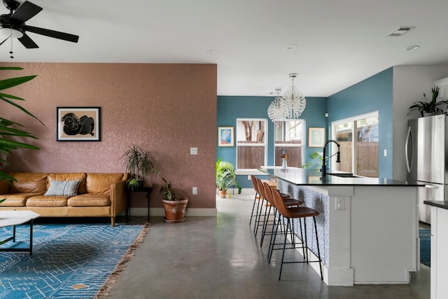 kitchen featuring concrete floors, a sink, dark countertops, a chandelier, and freestanding refrigerator