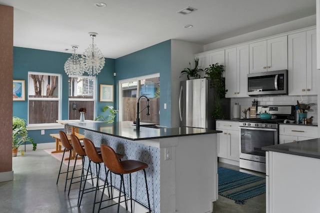 2912 Govalle Ave Unit A, Austin, TX 78702 - kitchen featuring appliances with stainless steel finishes, finished concrete floors, dark countertops, decorative backsplash, and a chandelier