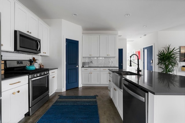 kitchen with stainless steel appliances, dark countertops, a sink, finished concrete floors, and decorative backsplash