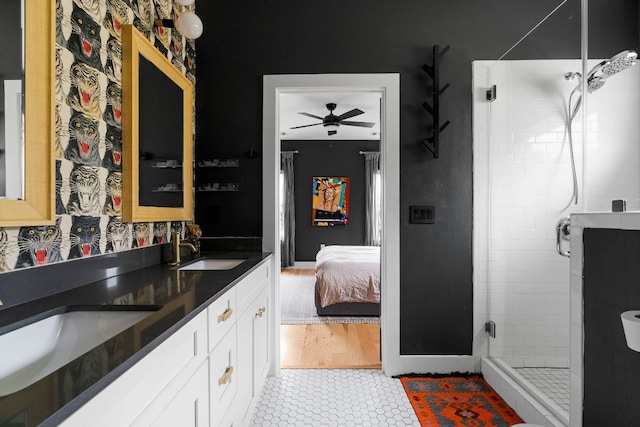 ensuite bathroom with a stall shower, a ceiling fan, double vanity, and tile patterned flooring