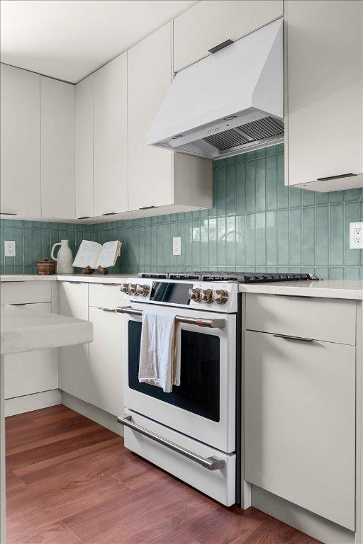 3605 Tallison Ter, Austin, TX 78704 - kitchen with white gas range oven, range hood, decorative backsplash, white cabinets, and light countertops