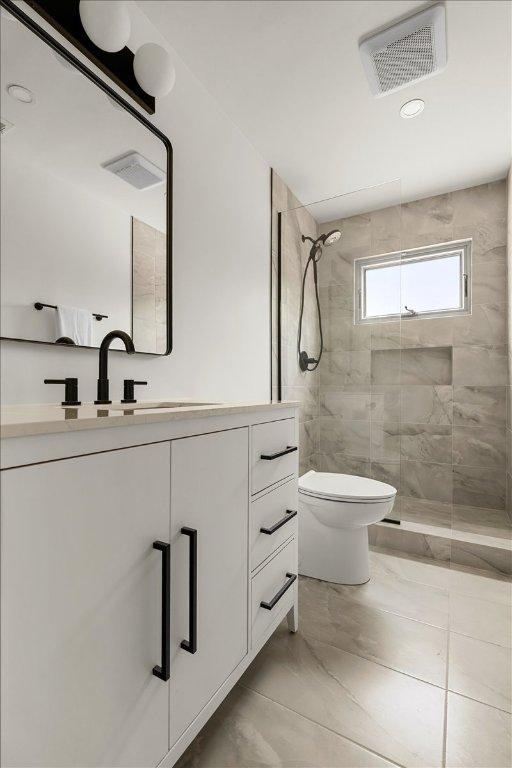 3605 Tallison Ter, Austin, TX 78704 - bathroom with a tile shower, vanity, and marble look tile flooring