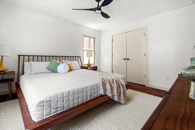 bedroom featuring wood finished floors, a closet, baseboards, and a ceiling fan