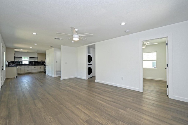 710 E 2nd St, Elgin, TX 78621 - unfurnished living room featuring a ceiling fan, stacked washer and clothes dryer, dark wood finished floors, and recessed lighting