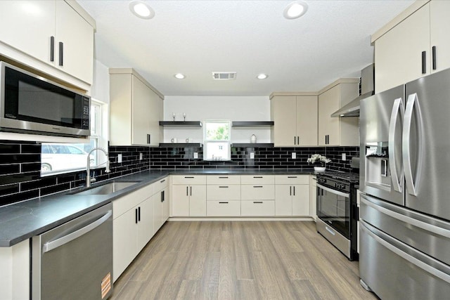 710 E 2nd St, Elgin, TX 78621 - kitchen featuring stainless steel appliances, open shelves, dark countertops, light wood-style flooring, and recessed lighting
