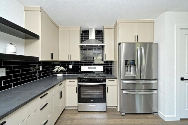 710 E 2nd St, Elgin, TX 78621 - kitchen featuring appliances with stainless steel finishes, wall chimney exhaust hood, dark countertops, wood finished floors, and cream cabinetry