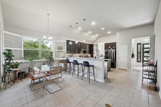 110 N Sage Holw, Dripping Springs, TX 78620 - kitchen with dark brown cabinetry, a peninsula, vaulted ceiling, light tile patterned floors, and a breakfast bar