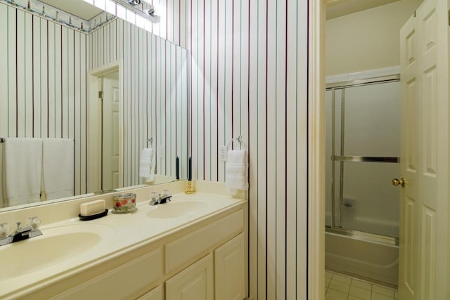 bathroom with double vanity, bath / shower combo with glass door, and tile patterned flooring