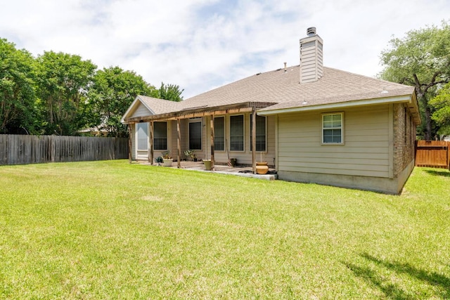 back of property with a chimney, a shingled roof, and a patio