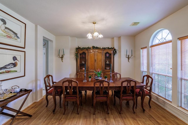 dining room featuring light wood finished floors, a chandelier, and baseboards