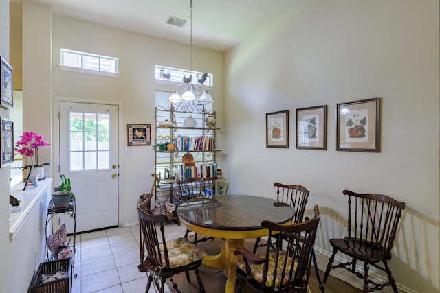 dining area with a towering ceiling, light tile patterned floors, and a chandelier