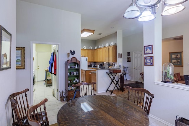 dining room featuring light tile patterned flooring, baseboards, and a towering ceiling