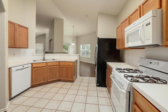 kitchen with white appliances, a sink, a peninsula, light countertops, and vaulted ceiling