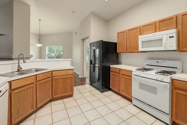 kitchen with white appliances, a sink, light countertops, light tile patterned flooring, and hanging light fixtures