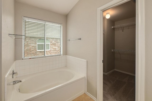 full bath with a walk in closet and a garden tub