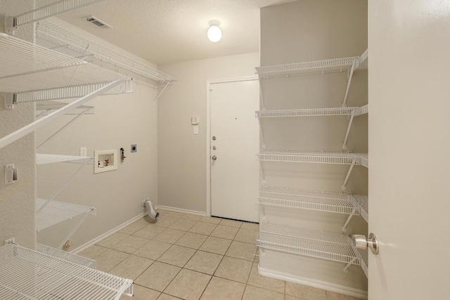 laundry area with hookup for an electric dryer, hookup for a washing machine, tile patterned floors, and baseboards