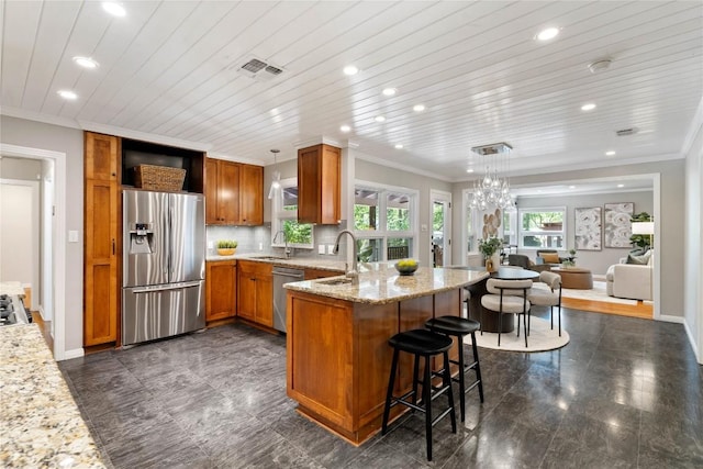 2601 W 49th St, Austin, TX 78731 - kitchen featuring appliances with stainless steel finishes, a peninsula, recessed lighting, brown cabinetry, and light stone counters