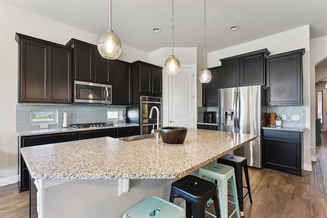 125 Redtail Ln, Leander, TX 78641 - kitchen with appliances with stainless steel finishes, backsplash, light wood finished floors, and a breakfast bar area