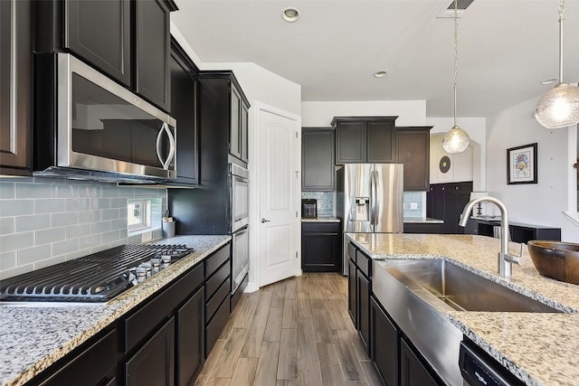 125 Redtail Ln, Leander, TX 78641 - kitchen with appliances with stainless steel finishes, a sink, light wood-style flooring, tasteful backsplash, and light stone countertops