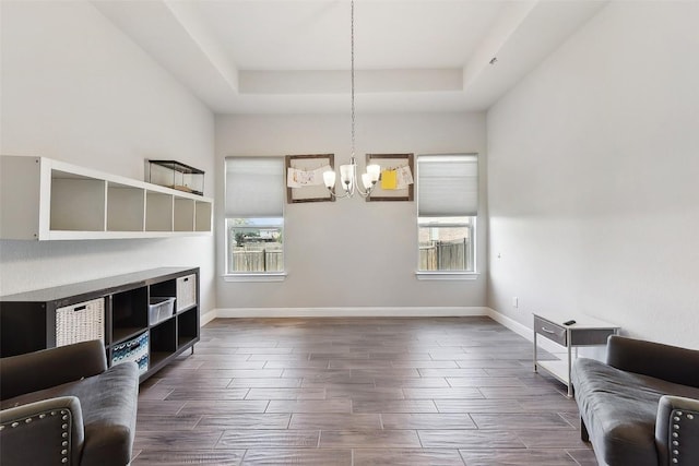 125 Redtail Ln, Leander, TX 78641 - unfurnished living room featuring a chandelier, a raised ceiling, wood tiled floors, and baseboards