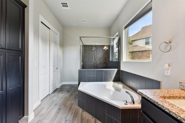 125 Redtail Ln, Leander, TX 78641 - full bathroom featuring tiled shower, a garden tub, vanity, and wood finished floors