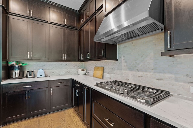 1616 Illawarra Way, Leander, TX 78641 - kitchen with ventilation hood, stainless steel gas stovetop, tasteful backsplash, dark brown cabinets, and light wood-style floors