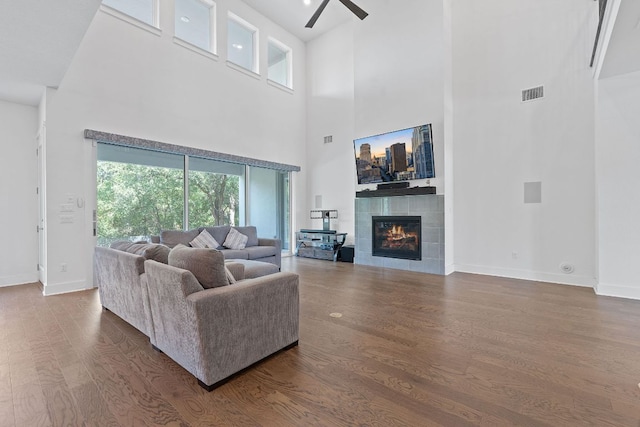 1616 Illawarra Way, Leander, TX 78641 - living room with a high ceiling, a ceiling fan, wood finished floors, a tiled fireplace, and baseboards