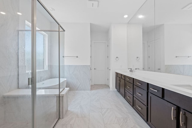 1616 Illawarra Way, Leander, TX 78641 - full bathroom with tile walls, a soaking tub, double vanity, a shower stall, and wainscoting