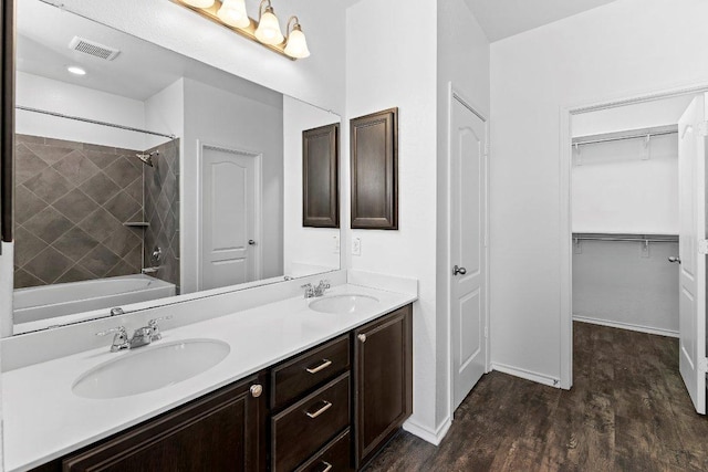 7604 Nunsland Dr, Austin, TX 78744 - bathroom featuring double vanity, wood finished floors, shower / bath combination, a spacious closet, and baseboards